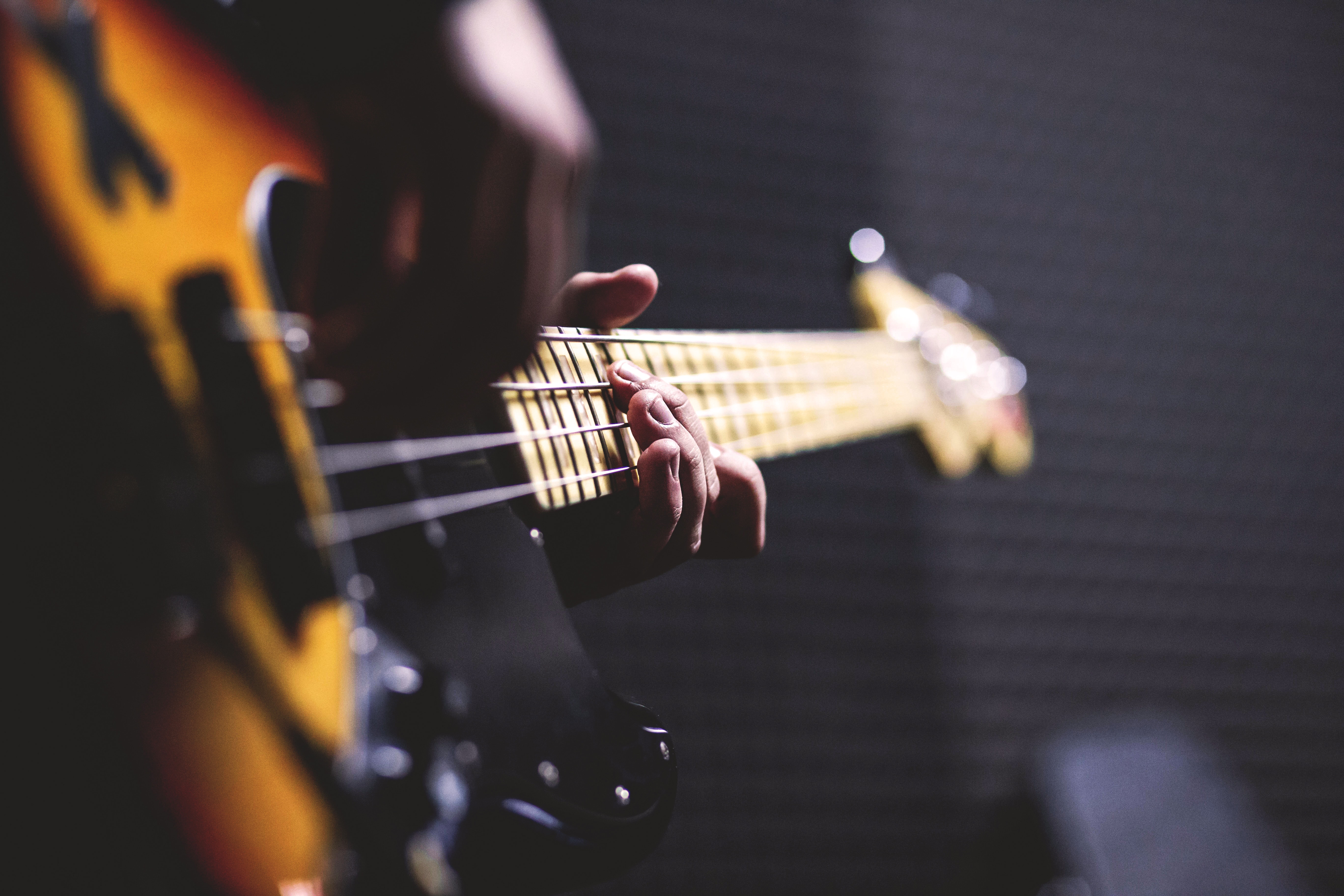 person-playing-sun-burst-electric-bass-guitar-in-bokeh-96380.jpg